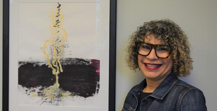 Dr. Alma Hoffman, an assistant professor of graphic design, poses with her painting 'Micah 4' which was named by Creative Quarterly as one of the 100 Best Artworks of 2021. 